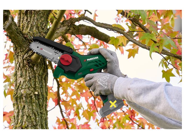 Persoon zaagt boomtak met compacte kettingzaag, herfstbladeren op de achtergrond.