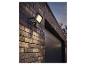 LED-schijnwerper met bewegingssensor op een bakstenen muur boven een garagedeur.