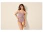 Vrouw in roze hemdje en slip, met hand in de zij.