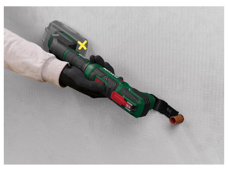 Persoon gebruikt een Parkside oscillerende multitool om een pijp in een muur te zagen.