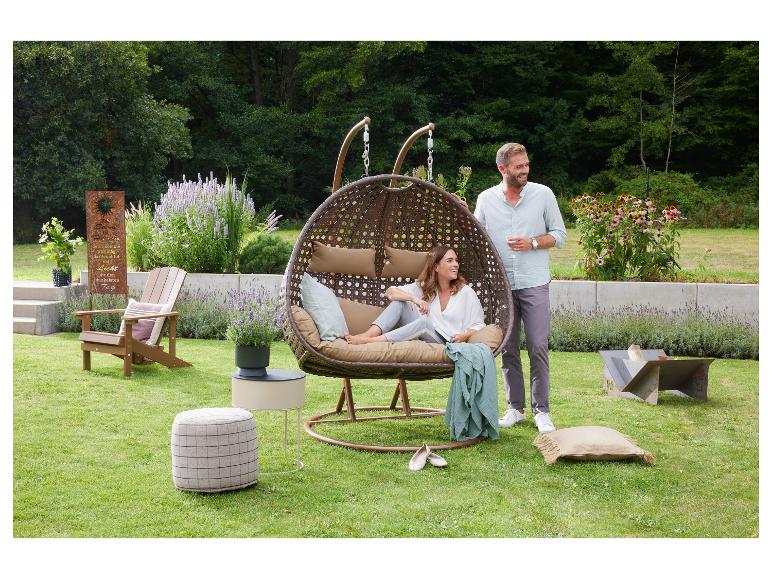 Paar in hangstoel in de tuin met tuinmeubelen en planten.