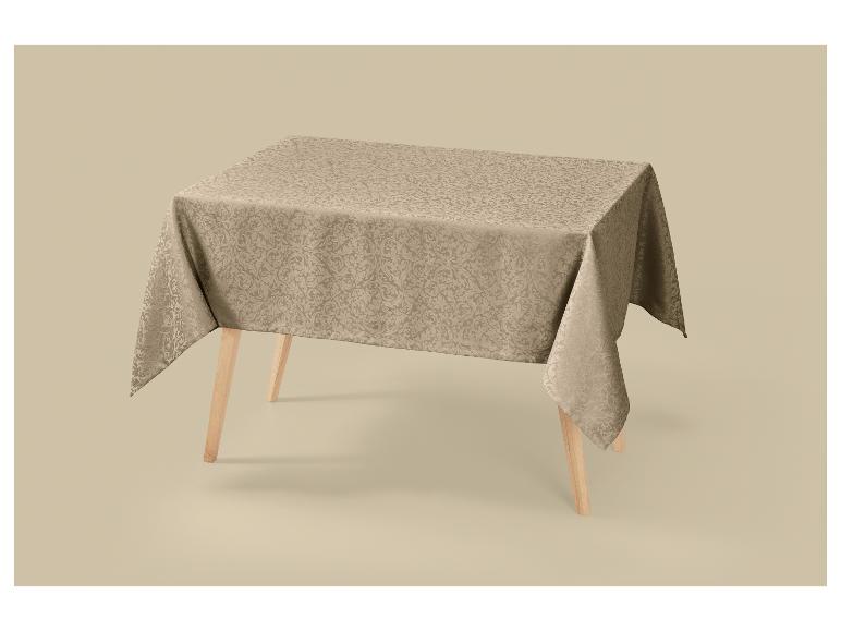 Beige tafelkleed met patroon, gedrapeerd over een houten tafel