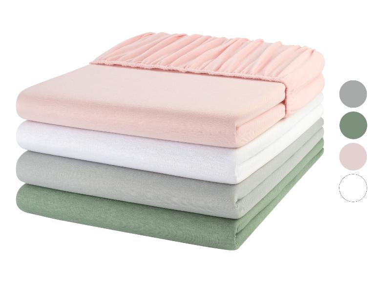 Een stapel roze, witte, grijze en groene lakens.