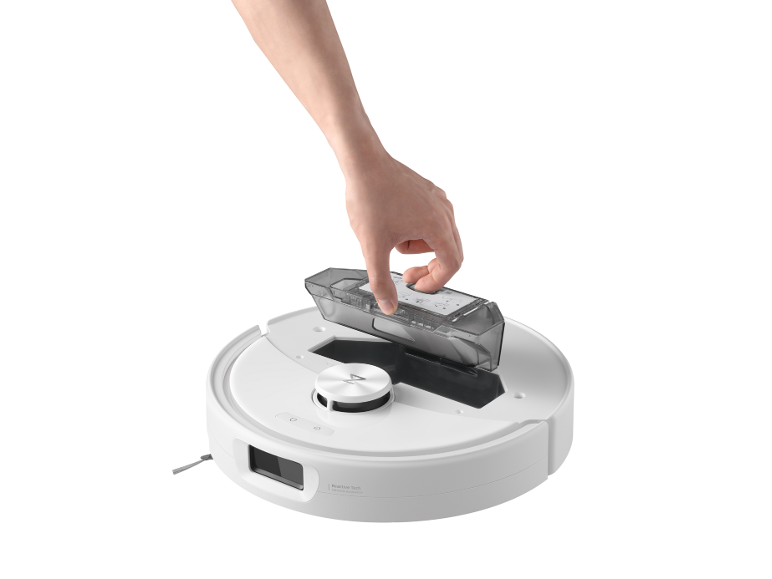 Hand plaatst transparante stofbak in witte robotstofzuiger.