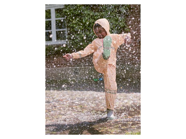Kind in regenkleding springt in een plas.