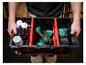 Man houdt gereedschapskist vast met accuboormachines, batterijen en spuitbussen.
