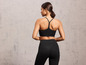 Een vrouw draagt een zwarte sportbeha en leggings.