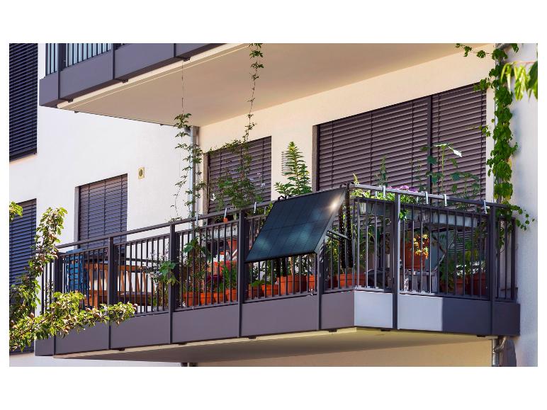 Een balkon met een zonnepaneel, planten en een metalen hek.