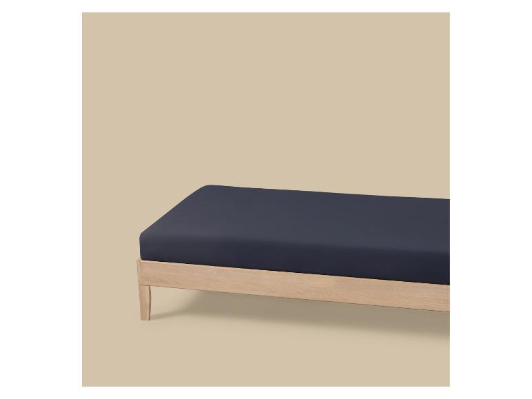 Donkerblauw hoeslaken op een licht houten bedframe.