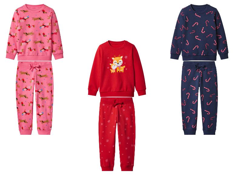 Drie sets kinderkerstpyjama's: roze met teckels, rood met rendieren en marineblauw met zuurstokken.