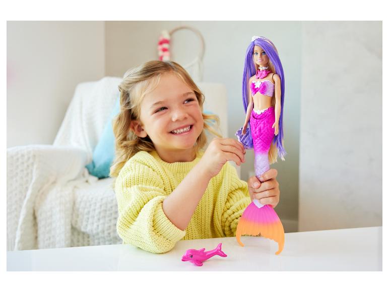 Lachend meisje speelt met een zeemeerminnenpop en een roze dolfijnspeeltje.