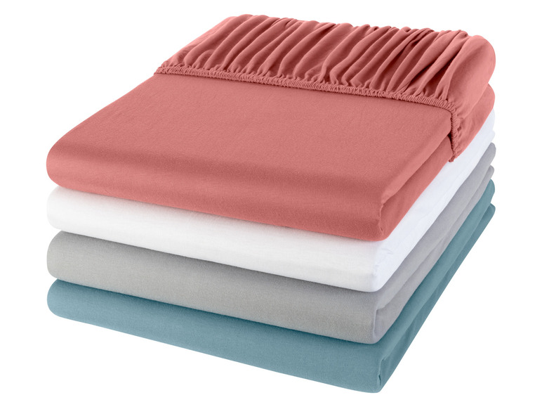 Een stapel bedlakens in verschillende kleuren.