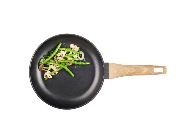 Groene bonen, champignons en uien gebakken in een pan.