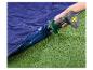 Elektrische luchtpomp blaast een blauw opblaasbaar matras op groen gras op.