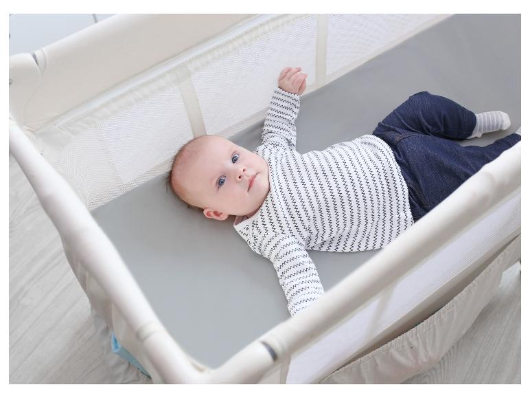 Baby in een wit en grijs ledikant