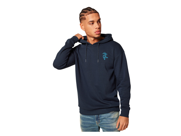 Een man draagt ​​een donkerblauwe hoodie met een klein logo