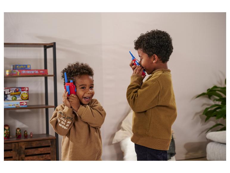 Twee jongens spelen met rode en blauwe walkietalkies in een kamer.