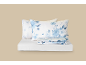 Wit beddengoed met blauw bloemenpatroon en een wit hoeslaken.