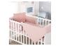Wit ledikant met roze beddengoed, kussen en bumper in een babykamer.