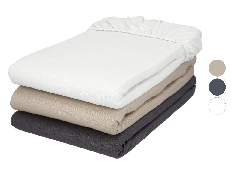 Stapels hoeslakens in wit, beige en donkergrijs met kleurstalen.