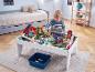 Jongen speelt met houten treintafel met bruggen en gebouwen in kinderkamer.