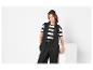 Vrouw in een zwart mouwloos colbert, gestreept T-shirt en zwarte broek.