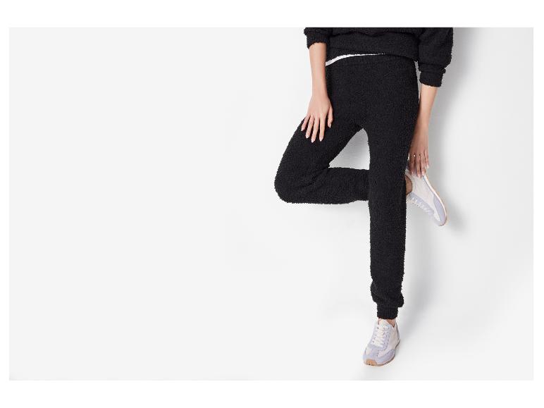 Zwart fleece trainingspak voor dames met sneakers.