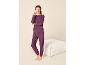 Lachende vrouw in een comfortabele, paarse loungewear set, bestaande uit een sweatshirt en joggingbroek.
