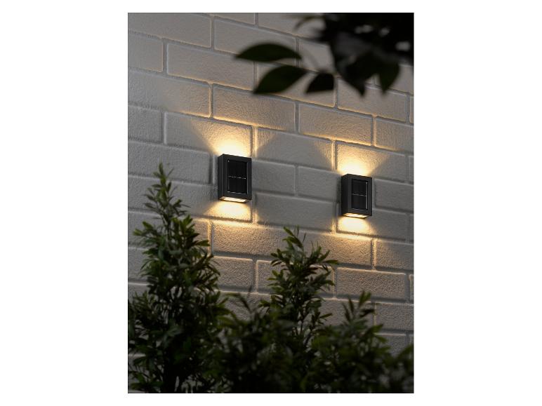 Twee solar lampen op een witte bakstenen muur.