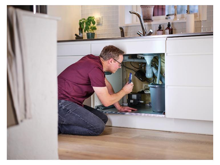 Man met LIVARNO® werklamp „The Inspector“ inspecteert onder de gootsteen.