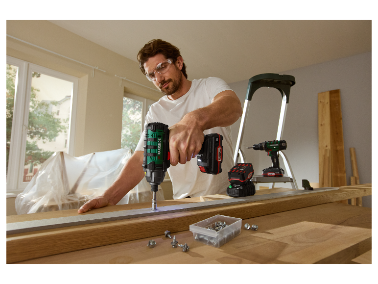 Een man gebruikt een Parkside accu-boormachine om met hout te werken.