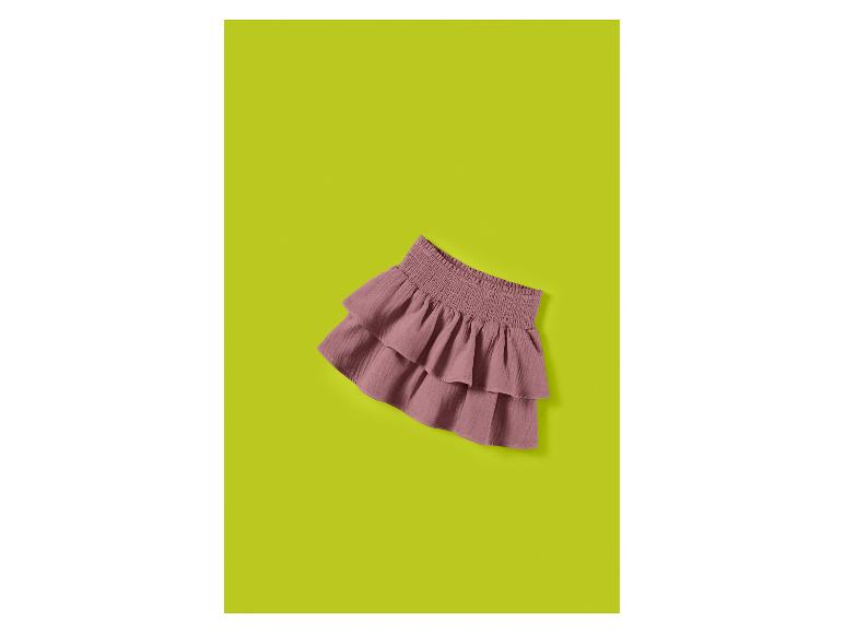Roze rucheskirt met een gesmokte tailleband, liggend op een limoengroene achtergrond.