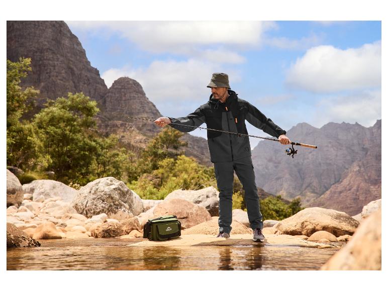 Man in visjas en -broek, met hoed, vissend in een bergbeek.