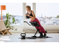 Een vrouw doet rugextensies op een verstelbare trainingsbank terwijl ze een kettlebell vasthoudt.