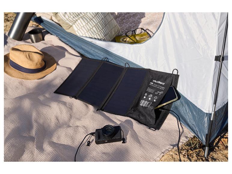 Een Crivit zonnelader met een smartphone en een camera in een tent.