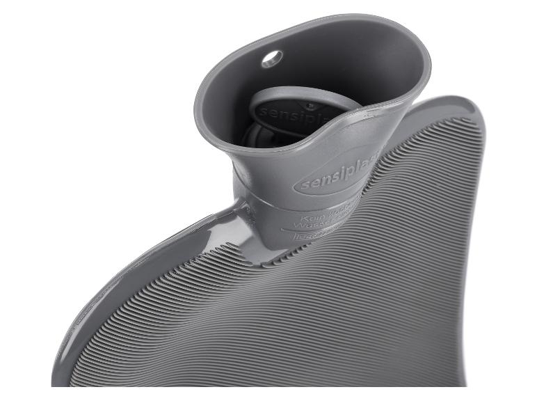 Grijze geribbelde kruik met de stop gedeeltelijk zichtbaar in de vulhals.