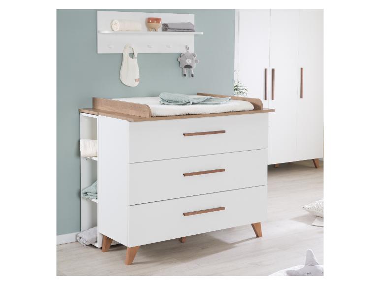 Witte commode met houten details en een witte plank met haken aan een lichtgroene muur.