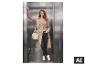 Vrouw in beige trenchcoat, zwarte jeans en witte sneakers in een lift.
