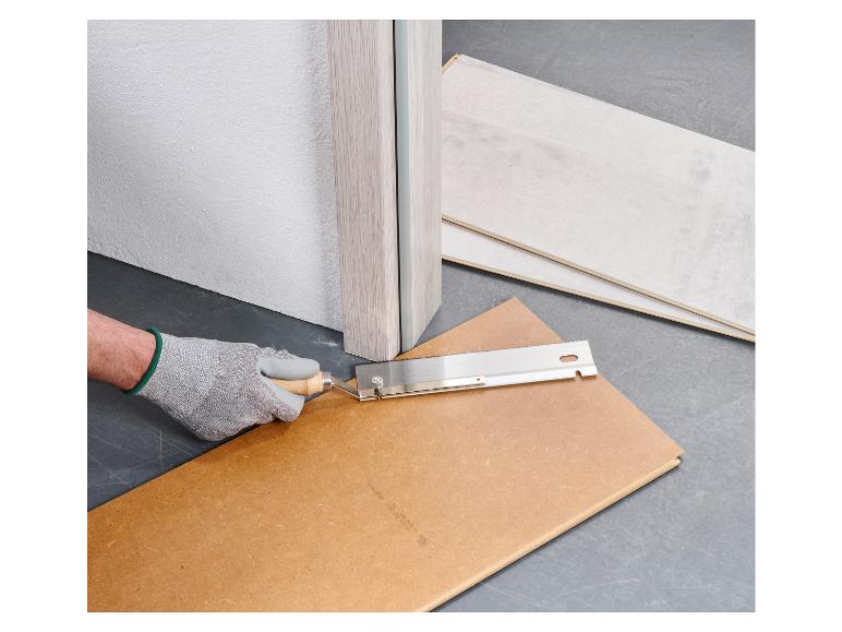 Een hand in een handschoen gebruikt een zaag om een houten plank te snijden.