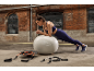 Vrouw doet een plank op een fitnessbal, met weerstandsbanden op de voorgrond.