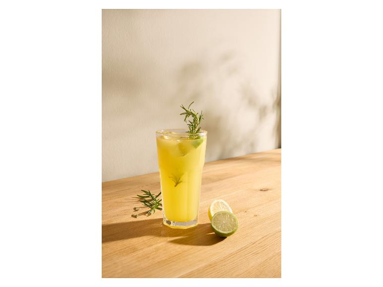 Glas limonade met rozemarijn en limoen op een houten tafel.