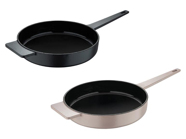 Twee gietijzeren pannen, één zwart en één beige, met handvat en een kleine greep.