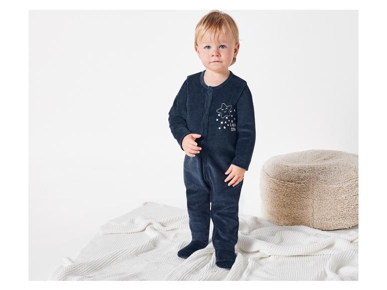 Baby in een donkerblauwe slaapzak met sterretjesmotief.