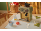 Speelgoedkoffiezetapparaat met accessoires, een kop warme chocolademelk en kerstdecoraties.