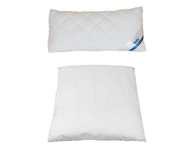 Twee witte kussens, de bovenste met een BeCo-label en een gewatteerd patroon.