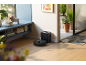 Robotstofzuiger met laadstation in een moderne woonkamer met planten en decoratie.