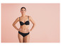 Een vrouw in zwarte lingerie poseert tegen een roze achtergrond.