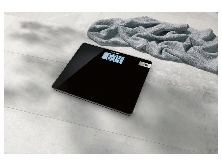 Zwarte SilverCrest badweegschaal met digitaal display en handdoek.