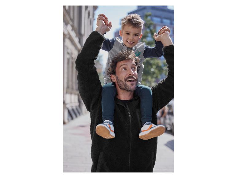 Een man draagt ​​zijn zoon op zijn schouders, beiden dragen winterkleding.