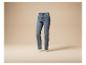 Blauwe gewassen damesjeans, zwevend op een beige achtergrond.